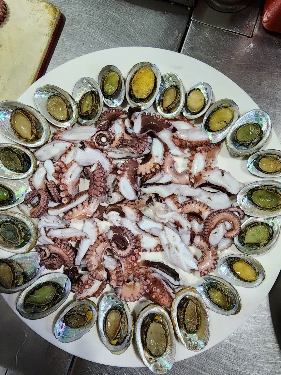 흰 접시에 둥글게 담은 오분자기와 가운데 놓인 돌문어 숙회